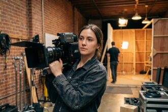 Étudiante en cinéma tenant une caméra professionnelle dans un studio d'école de film en France