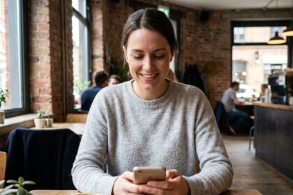 Jeune femme consultant son forfait mobile sans engagement sur smartphone dans un café urbain